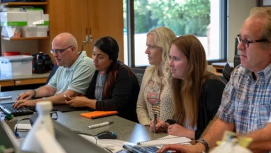 Five employees sitting at a desk discussing best texting software for nonprofits